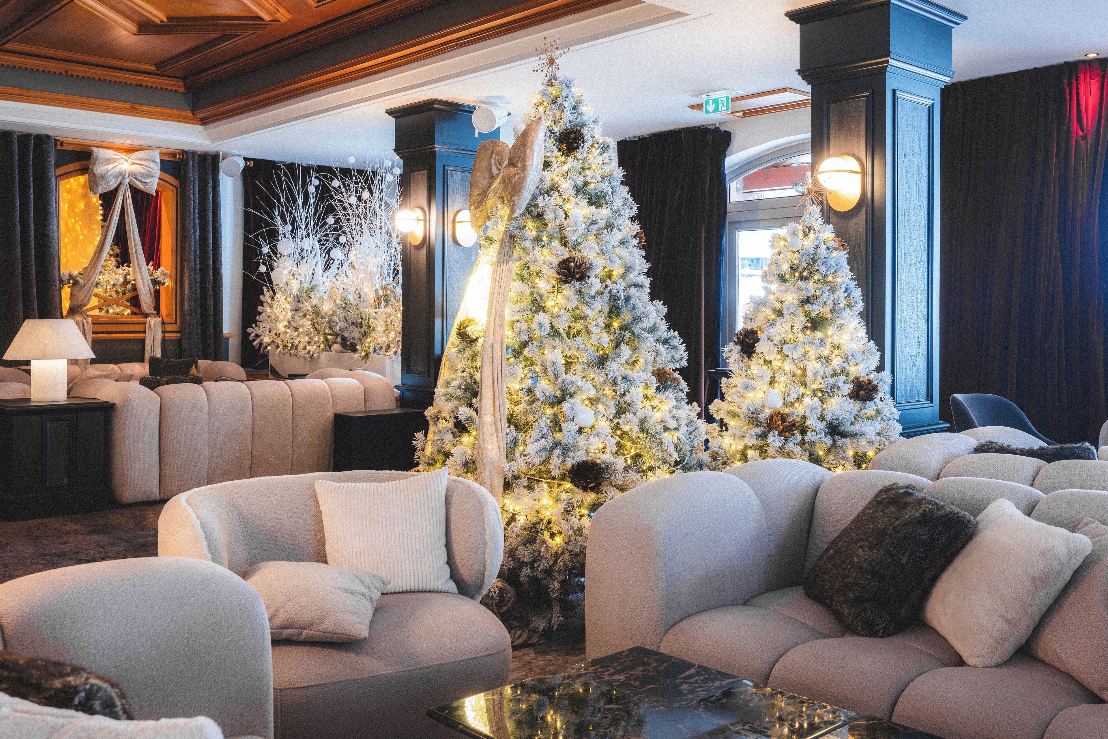 A lobby with plush seating, a large Christmas tree, and a chandelier.