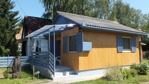 A wooden house with a porch, a staircase, and a small garden area. - Müllers Ferienhaus Gunaras (Dombovar)