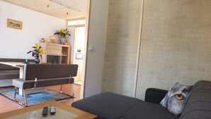 A living room with a grey sofa, a wooden coffee table, and a dining area with a bench. - Müllers Ferienhaus Gunaras (Dombovar)
