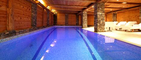 Een binnenzwembad en ligstoelen