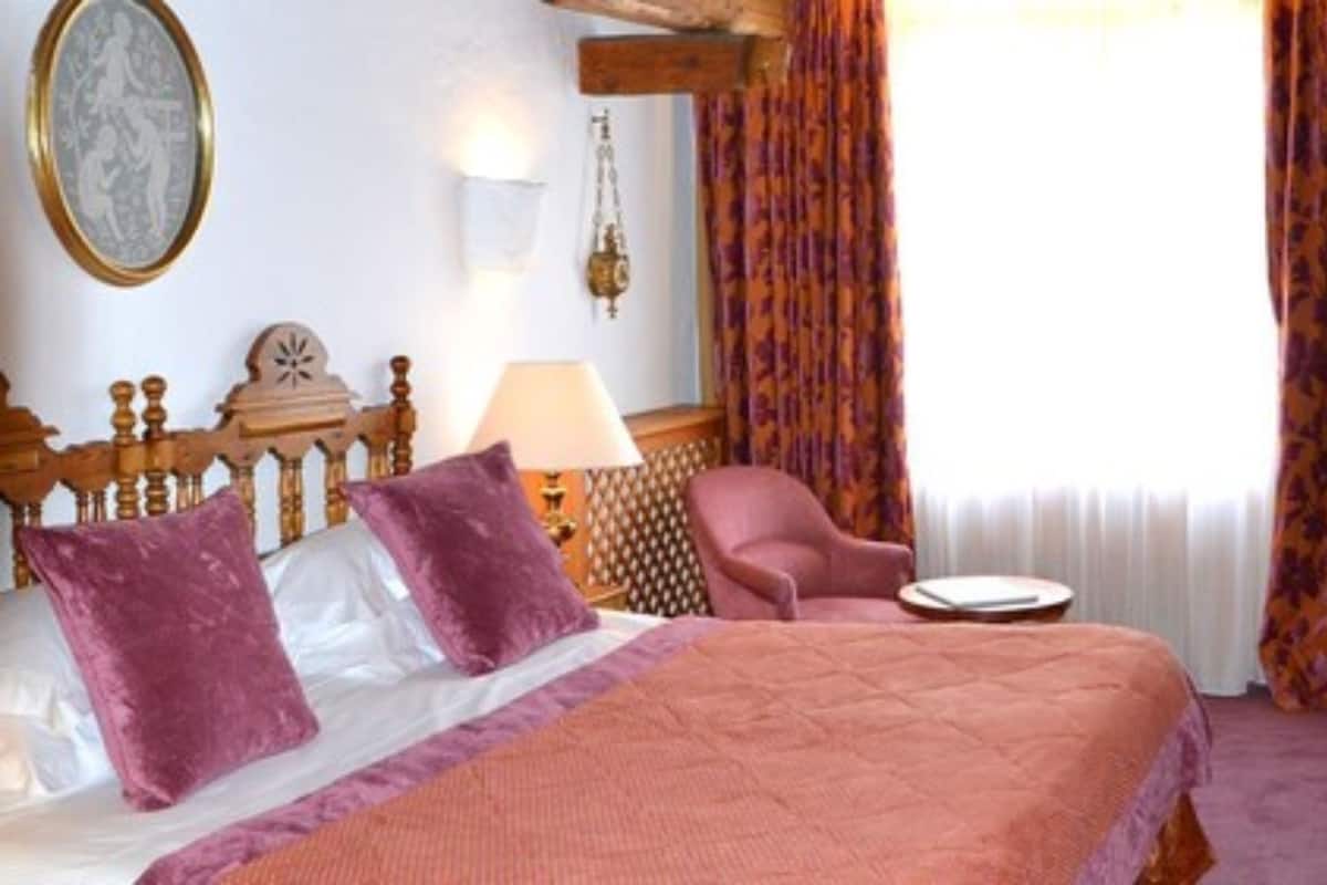 A hotel room with a bed, a chair, a table, and a television.
