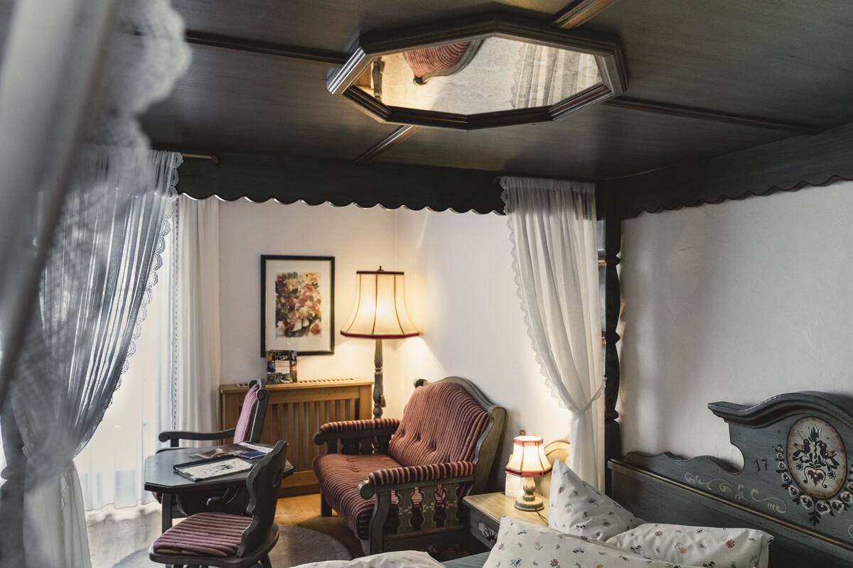 Une pièce confortable avec un lit, une chaise, une table et une lampe.