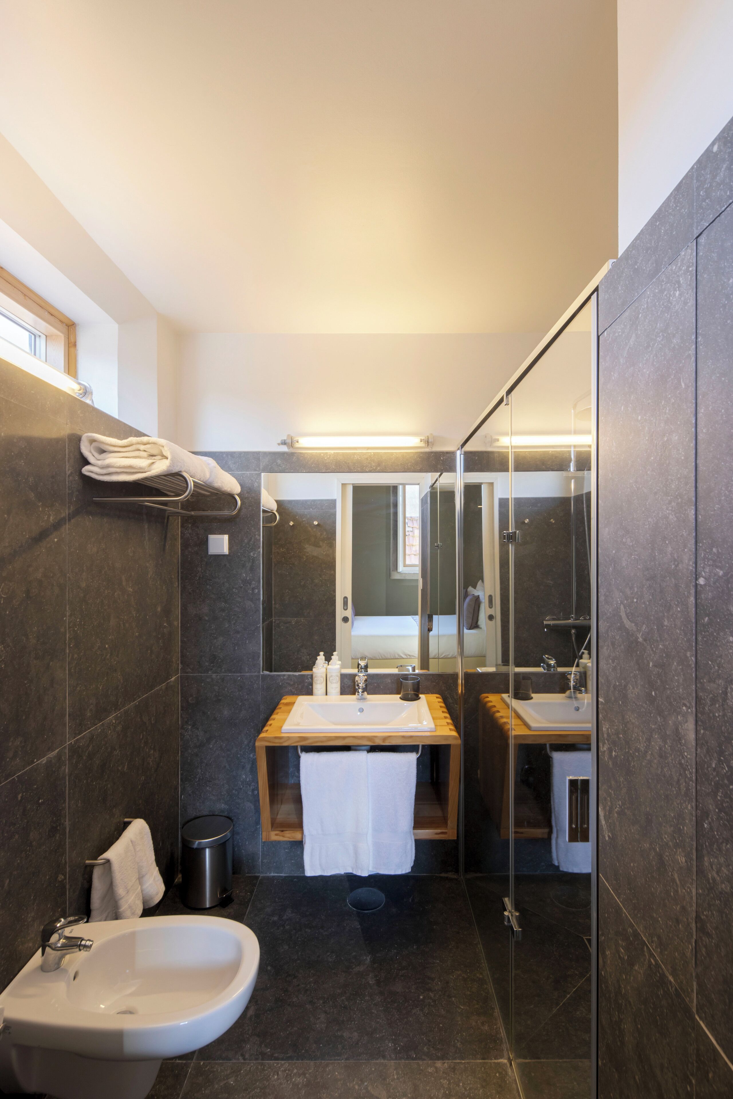 A modern bathroom with a glass shower enclosure, a sink, and a mirror.