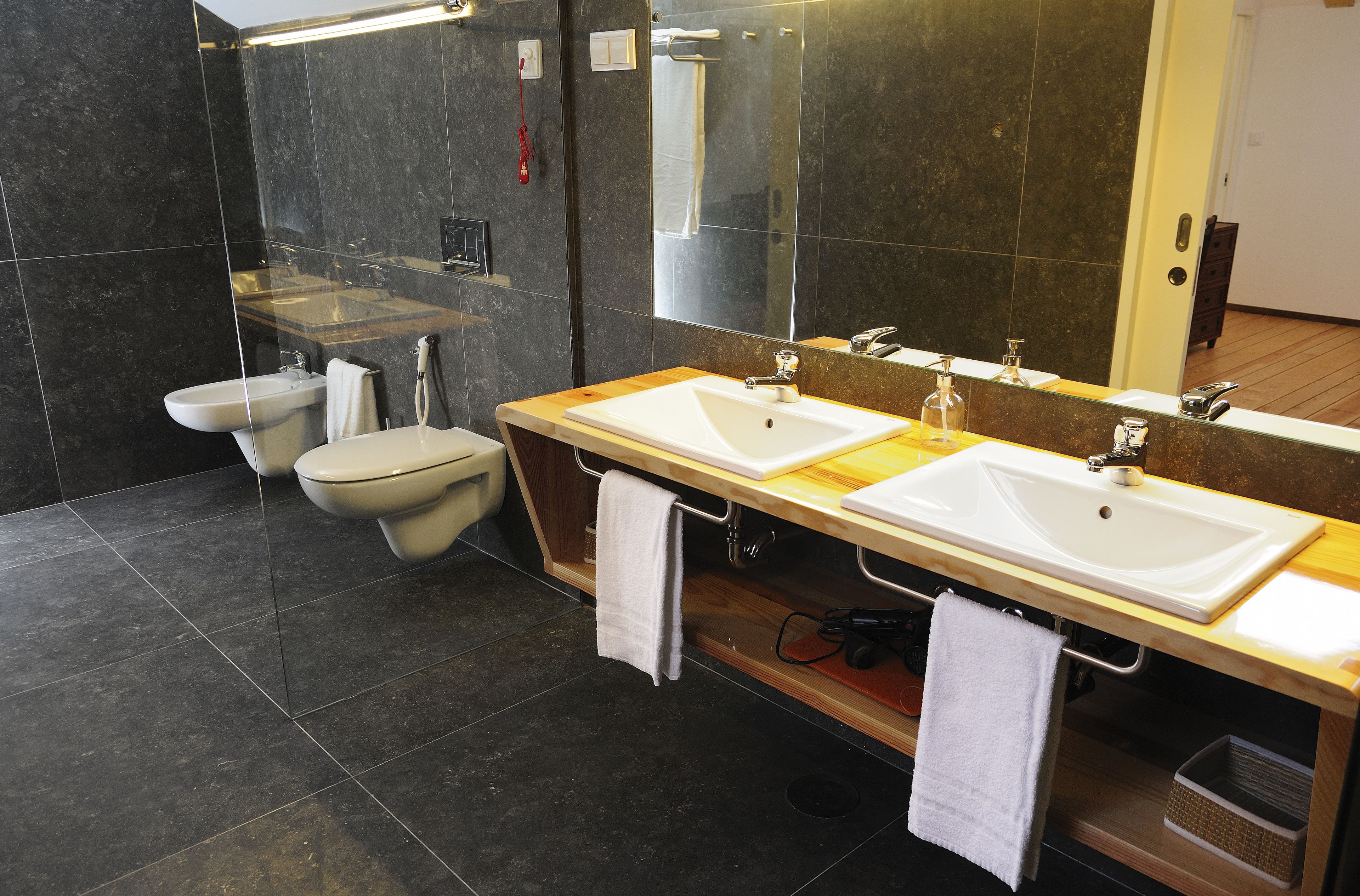 Een moderne badkamer met twee wastafels, een toilet en een grote spiegel.