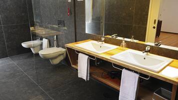Een moderne badkamer met twee wastafels, een toilet en een grote spiegel.