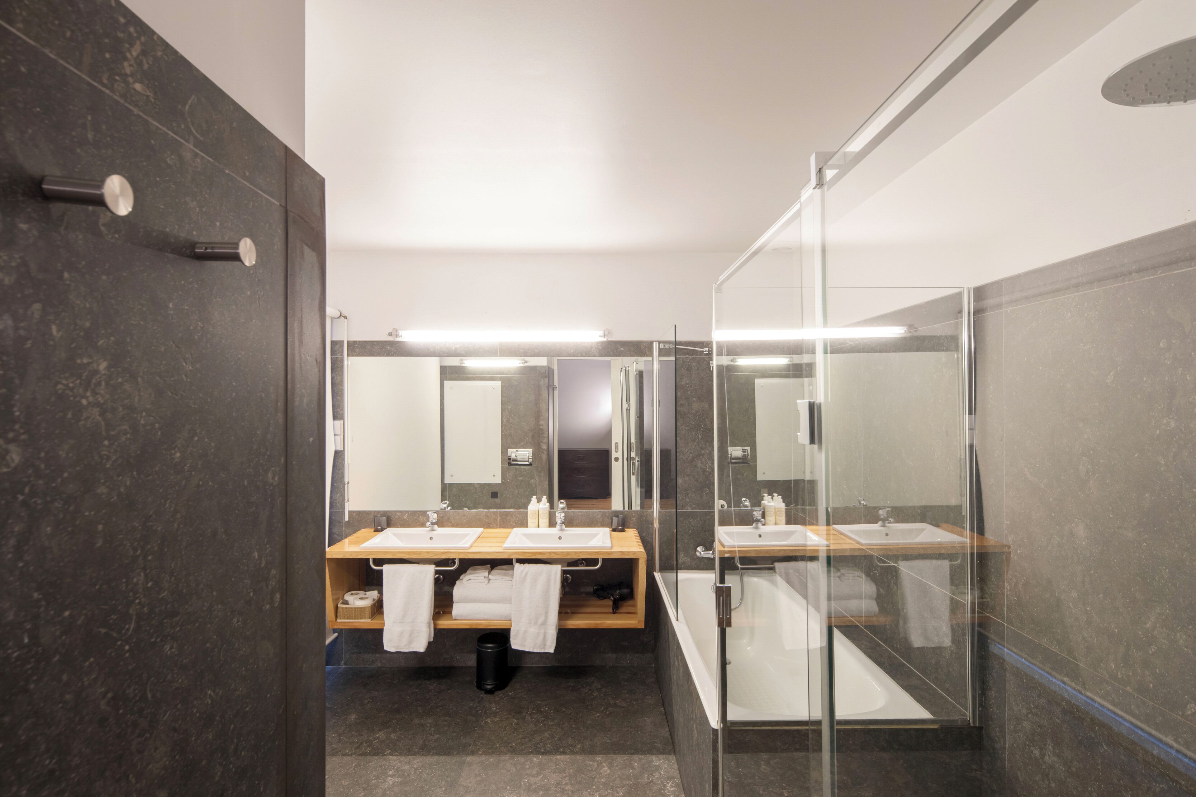 A modern bathroom with a glass-enclosed shower, two sinks, and a mirror.