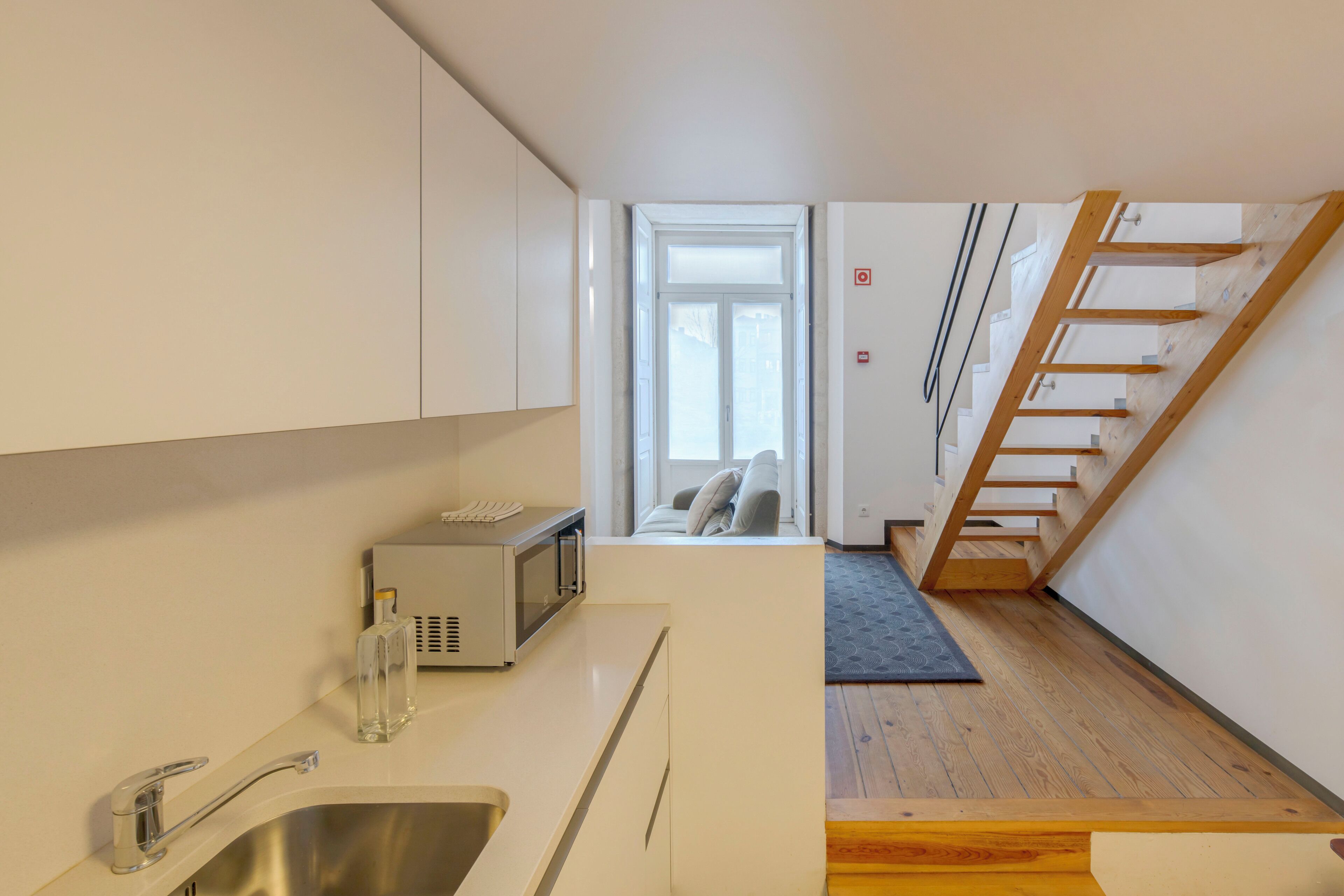 A modern kitchen with a stainless steel sink, a microwave, and a small countertop area.