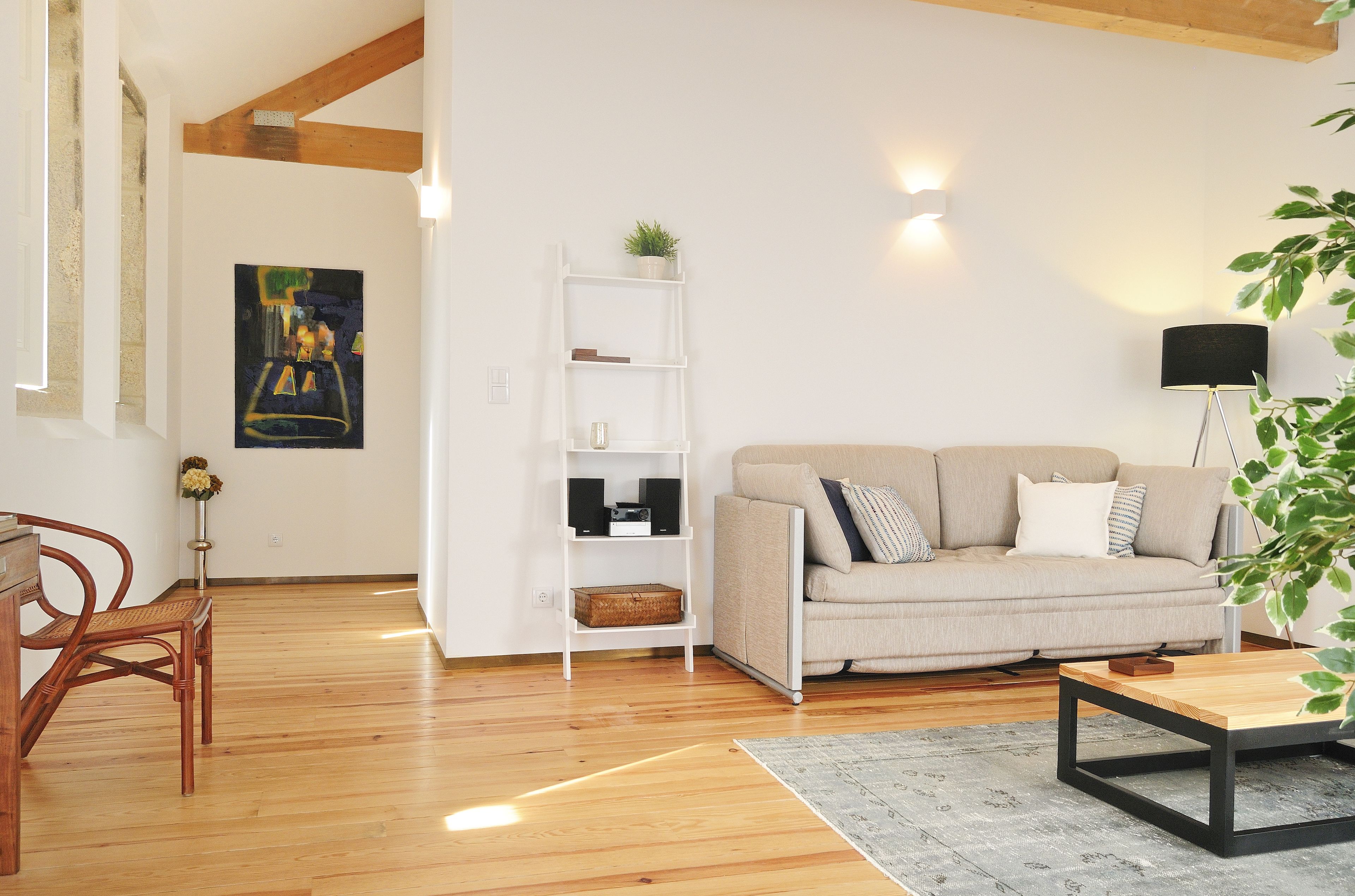 A living room with a sofa, a coffee table, a bookshelf, and a painting on the wall.