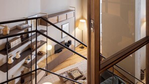 Ein modernes Interieur mit einer Holztreppe, einer Glastrennwand und einer gemütlichen Sitzecke mit Kissen.