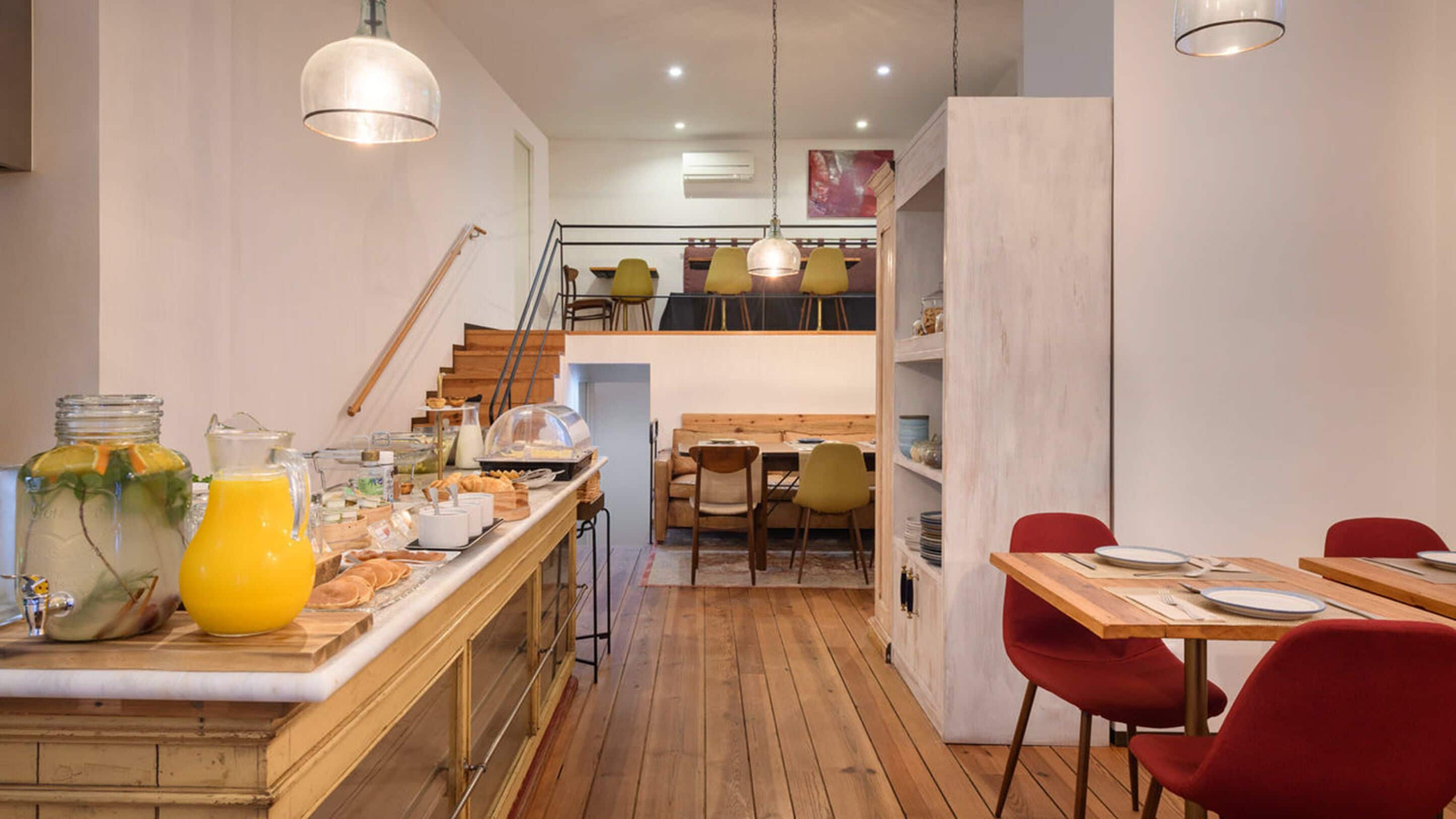 Une cuisine moderne avec des plans de travail en bois, un bar pour prendre le petit-déjeuner et un coin repas avec des chaises rouges.