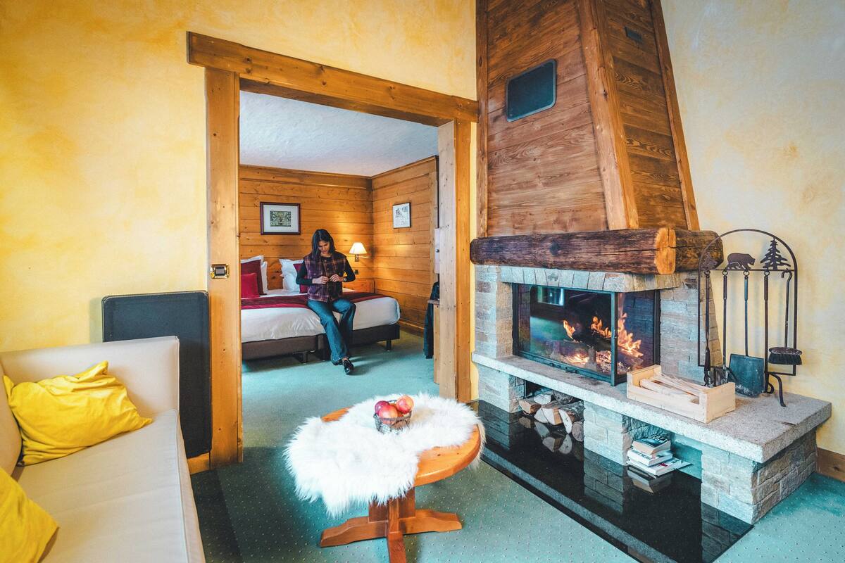 A cozy room with a stone fireplace, a wooden ceiling, and a bed with a yellow pillow.