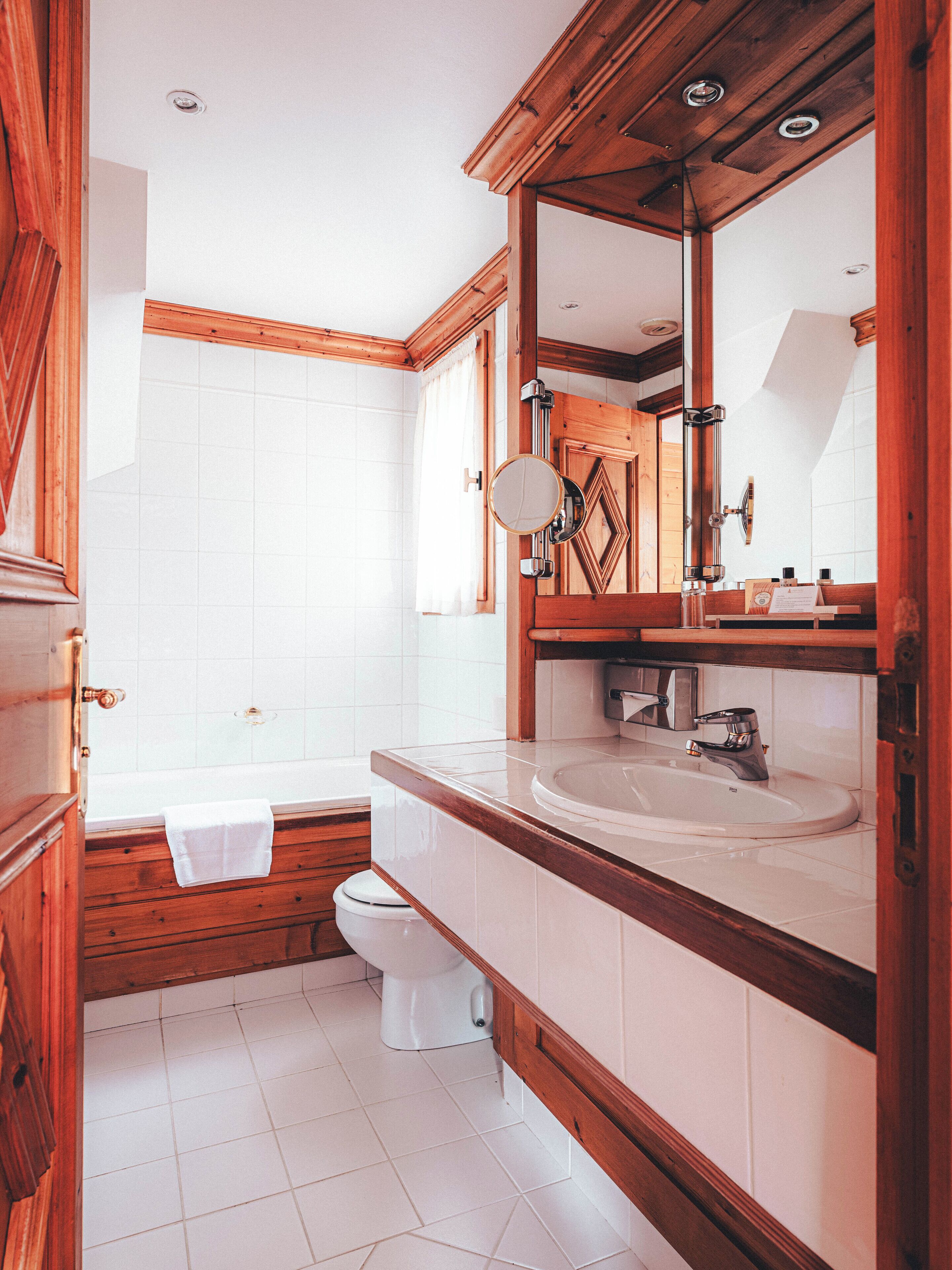 Een badkamer met een houten wastafelmeubel, een wastafel, een spiegel en een toilet.