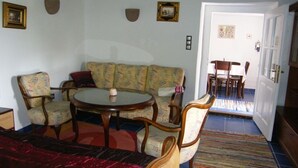A room with a sofa, two armchairs, a small table, and a door leading to a dining area. - Ferienhaus Leitenhof (Döbrököz)