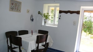 A dining area with a table set for four, a window with a view, and a door leading outside. - Ferienhaus Leitenhof (Döbrököz)