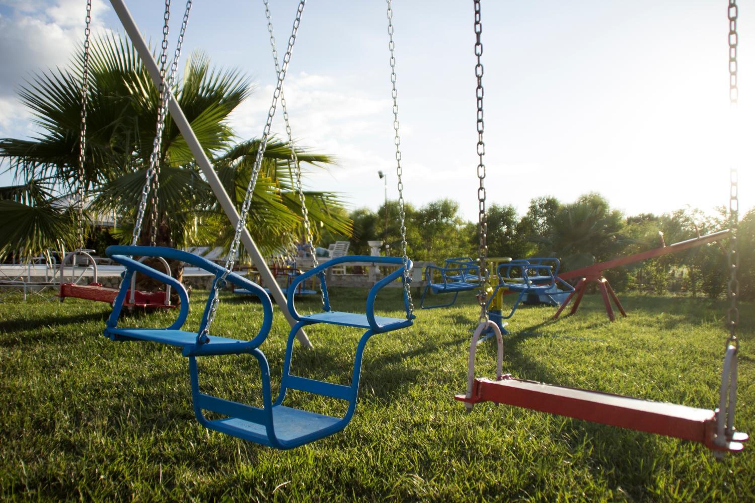 Ein Spielplatz mit Schaukeln und einer roten Wippe.