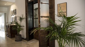 Un pasillo con una puerta de madera, plantas en macetas y cuadros en la pared.