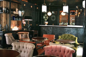 A bar area with wooden shelves, various bottles, and a mix of bar stools and chairs.