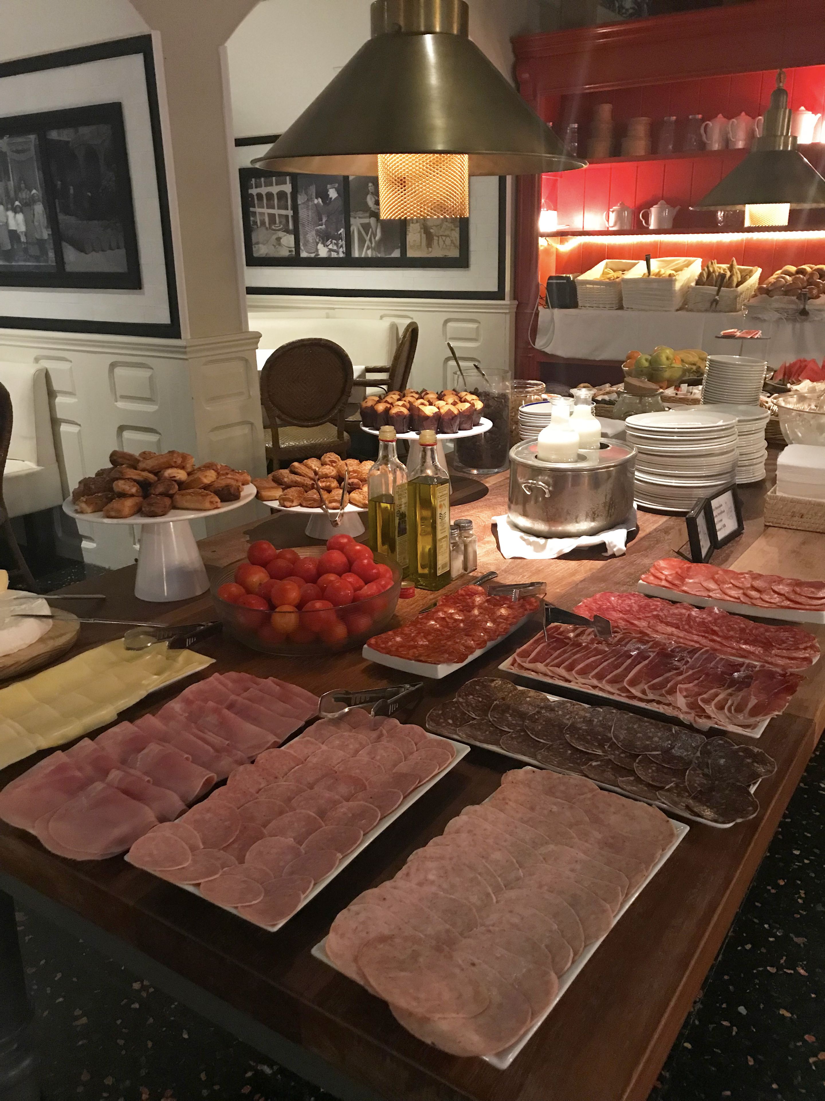 Un bufé con diversos alimentos, incluyendo carnes, pasteles y frutas.