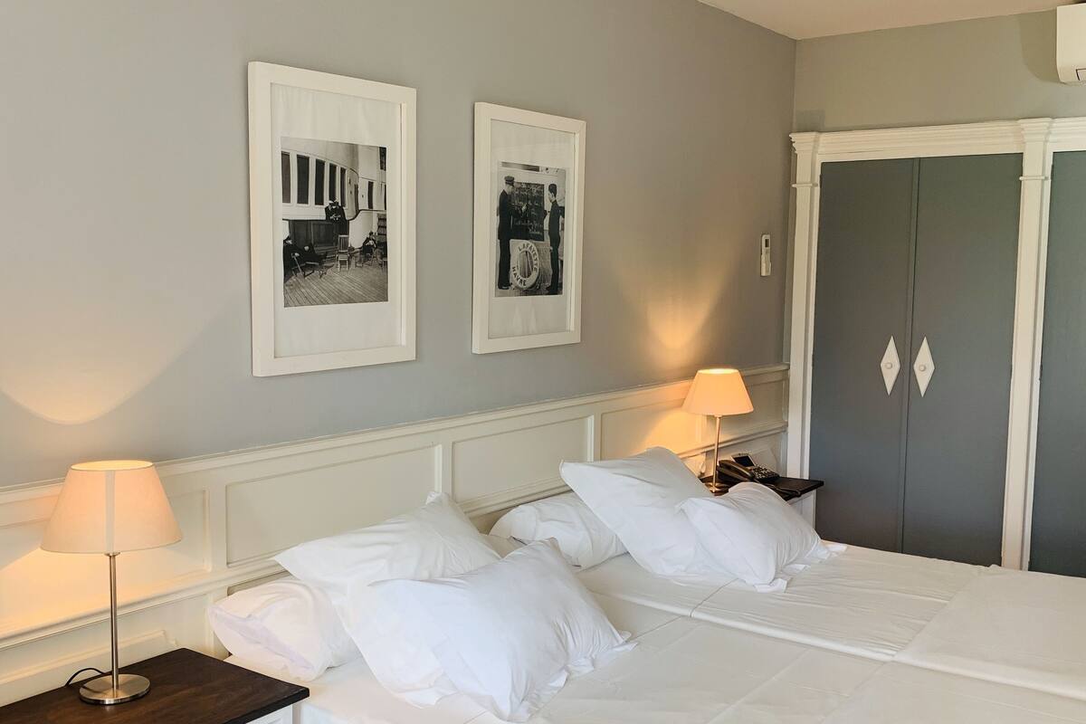 Ett hotellrum med en stor säng, två sängbord, en garderob och två inramade tavlor på väggen.