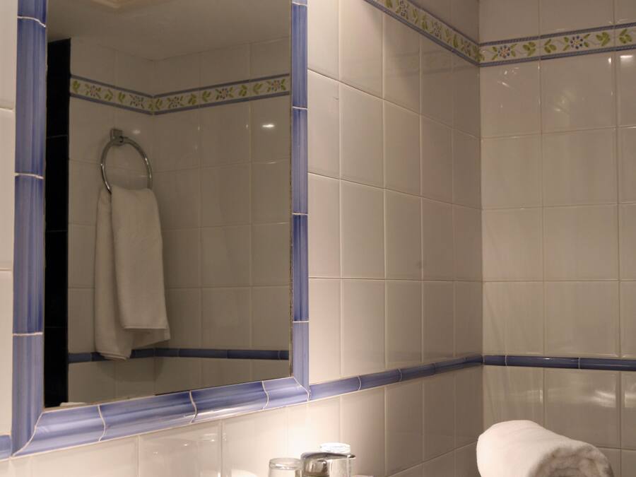 Un baño con un lavamanos blanco, un espejo con marco azul y una toalla sobre la encimera.