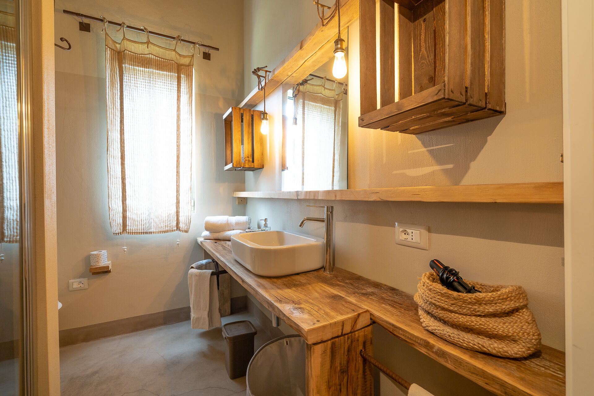 Ein Badezimmer mit einem Holzbadezimmerschrank, einem großen Spiegel und einer hängenden Leuchte.
