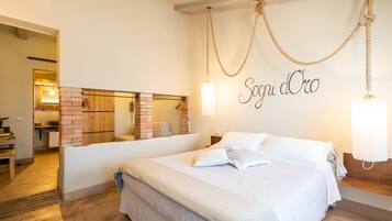 A hotel room with a large bed, a brick fireplace, and a wall-mounted sign reading "Sogni d'Oro".