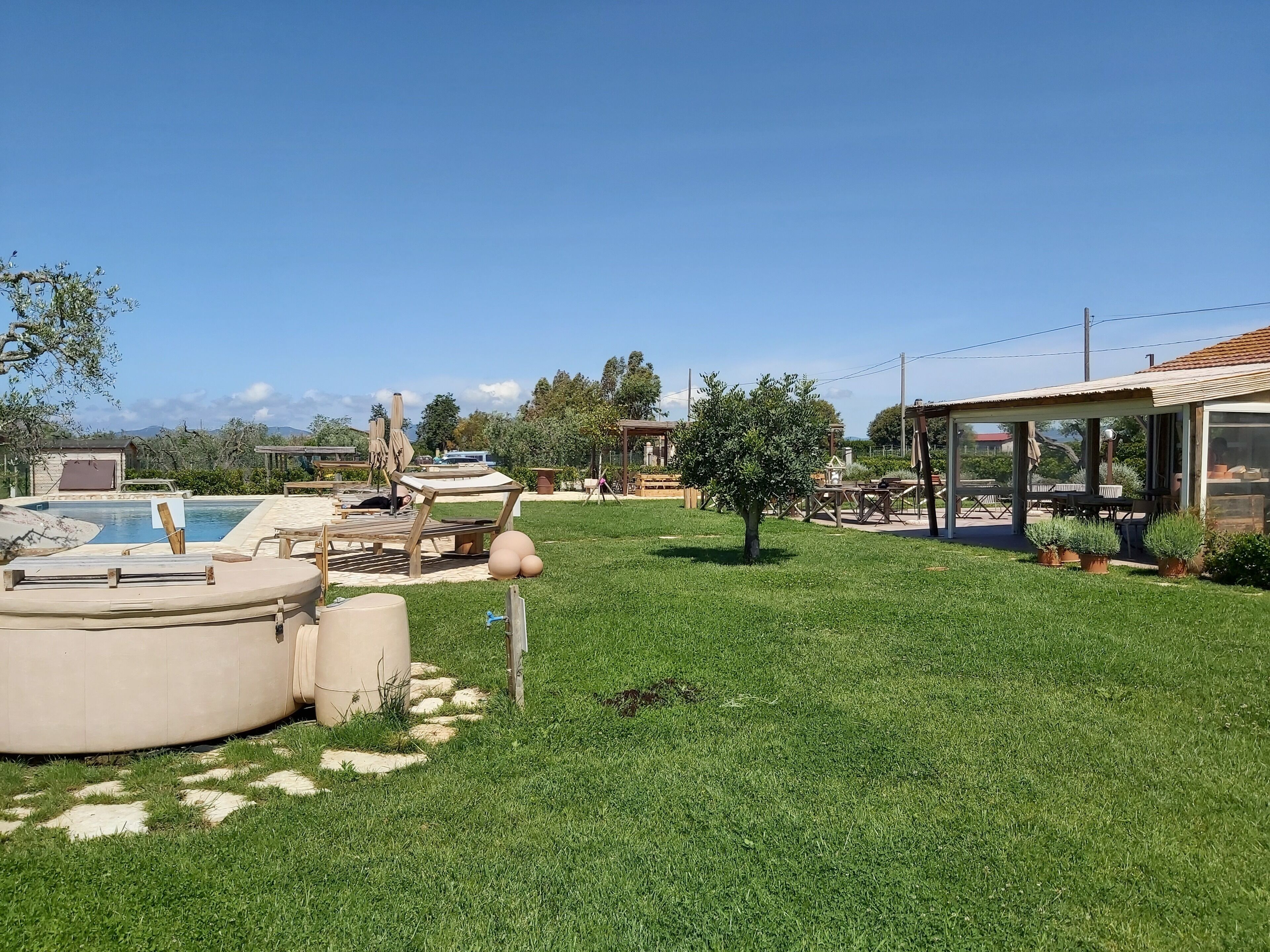 A backyard with a swimming pool, outdoor furniture, and a covered patio area.