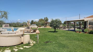 A backyard with a swimming pool, outdoor furniture, and a covered patio area.