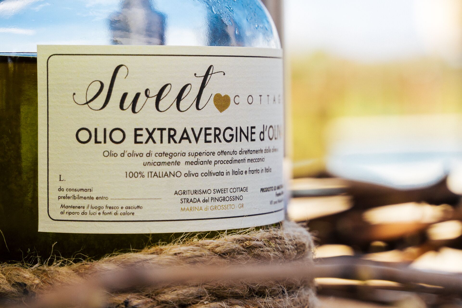 A bottle of Sweet Cottare olive oil with a label indicating it is 100% Italian, made from extra virgin olive oil, and produced by Agriturismo Sweet Cottage.