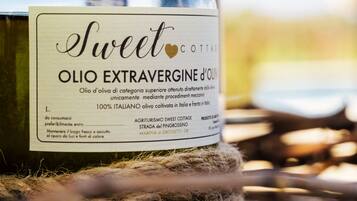 A bottle of Sweet Cottare olive oil with a label indicating it is 100% Italian, made from extra virgin olive oil, and produced by Agriturismo Sweet Cottage.