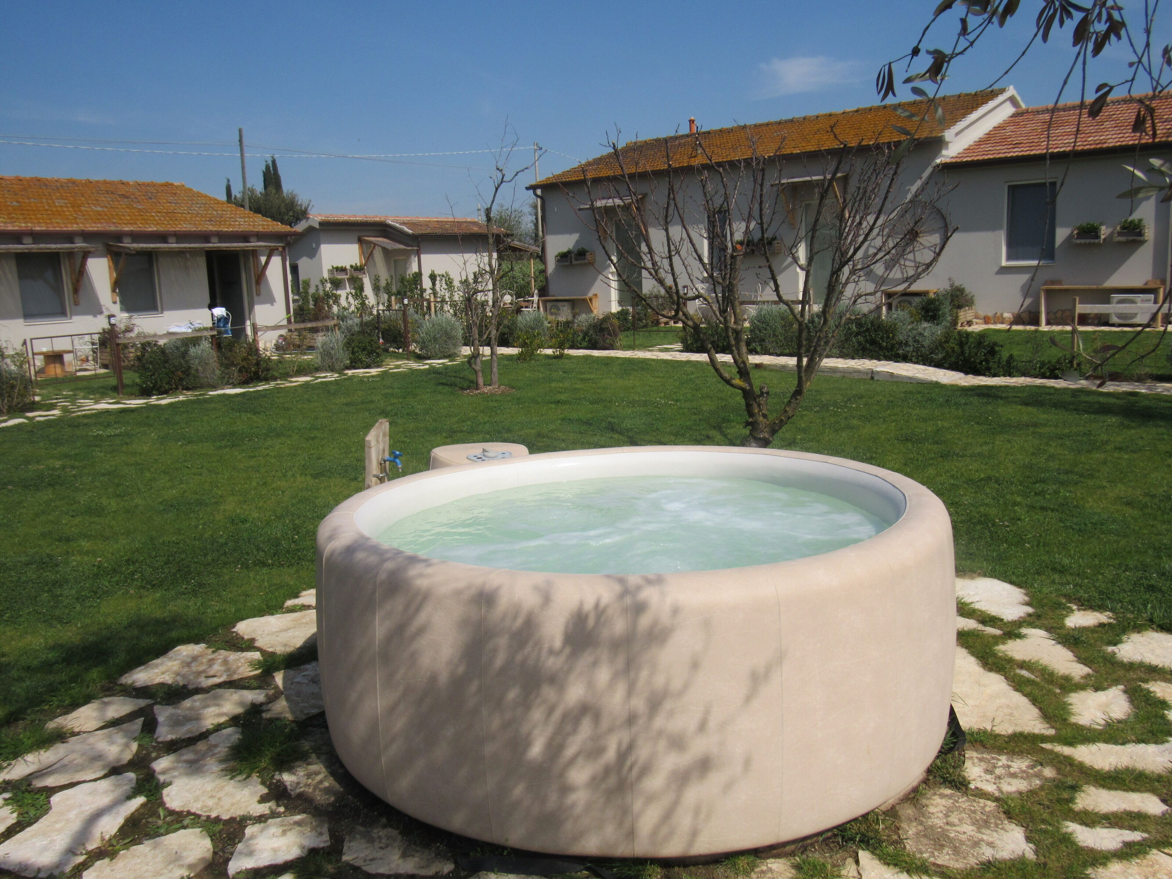 Un jacuzzi en un patio trasero con césped y una casa al fondo.
