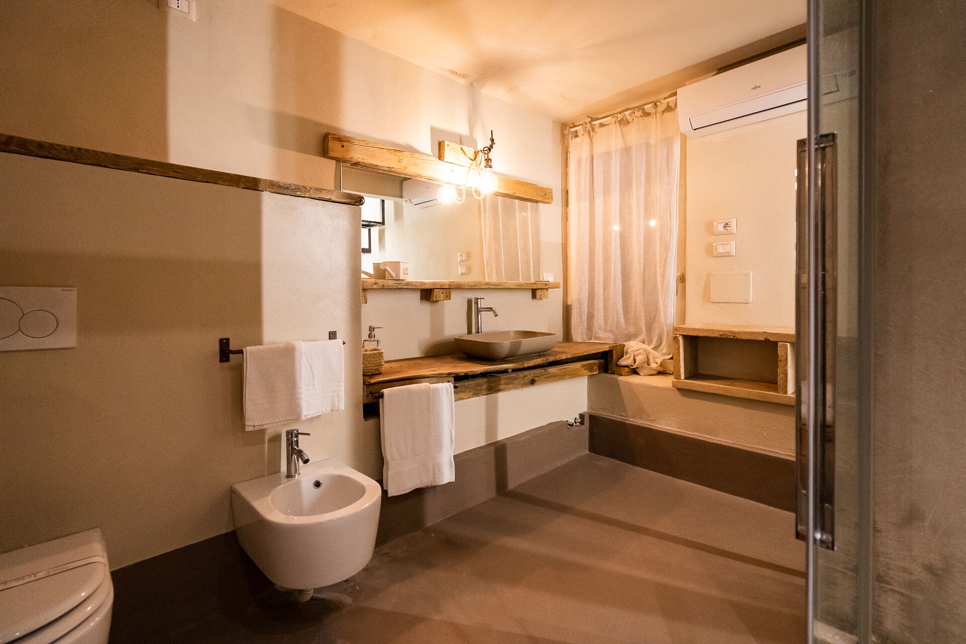 A bathroom with a bidet, sink, mirror, and shower.