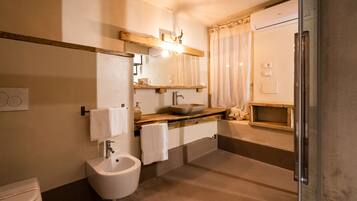 A bathroom with a bidet, sink, mirror, and shower.
