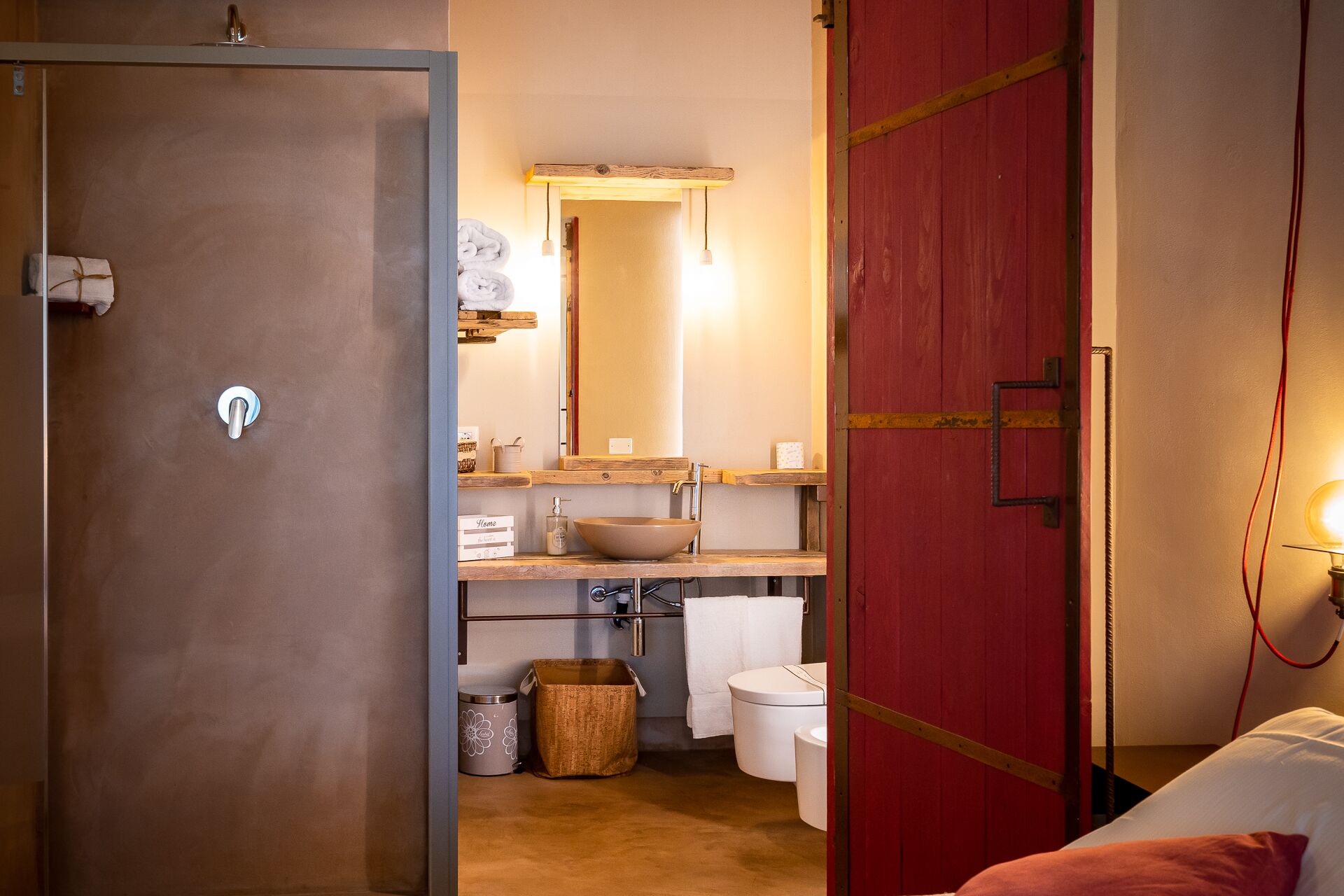 Un baño con tocador de madera, un espejo grande, lavabo tipo cuenco y un inodoro.