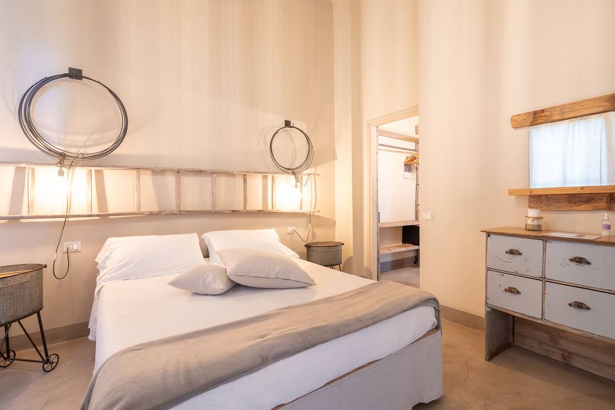 A bedroom with a bed, bedside tables, a dresser, and a mirror.