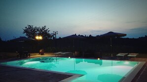 A swimming pool with a clear water surface, surrounded by a patio area with chairs and tables.