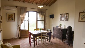A cozy room with a dining table, chairs, a sofa, a dresser, and a large window with curtains.