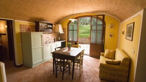 A compact kitchen with a dining area, a built-in oven, and a window overlooking a garden.
