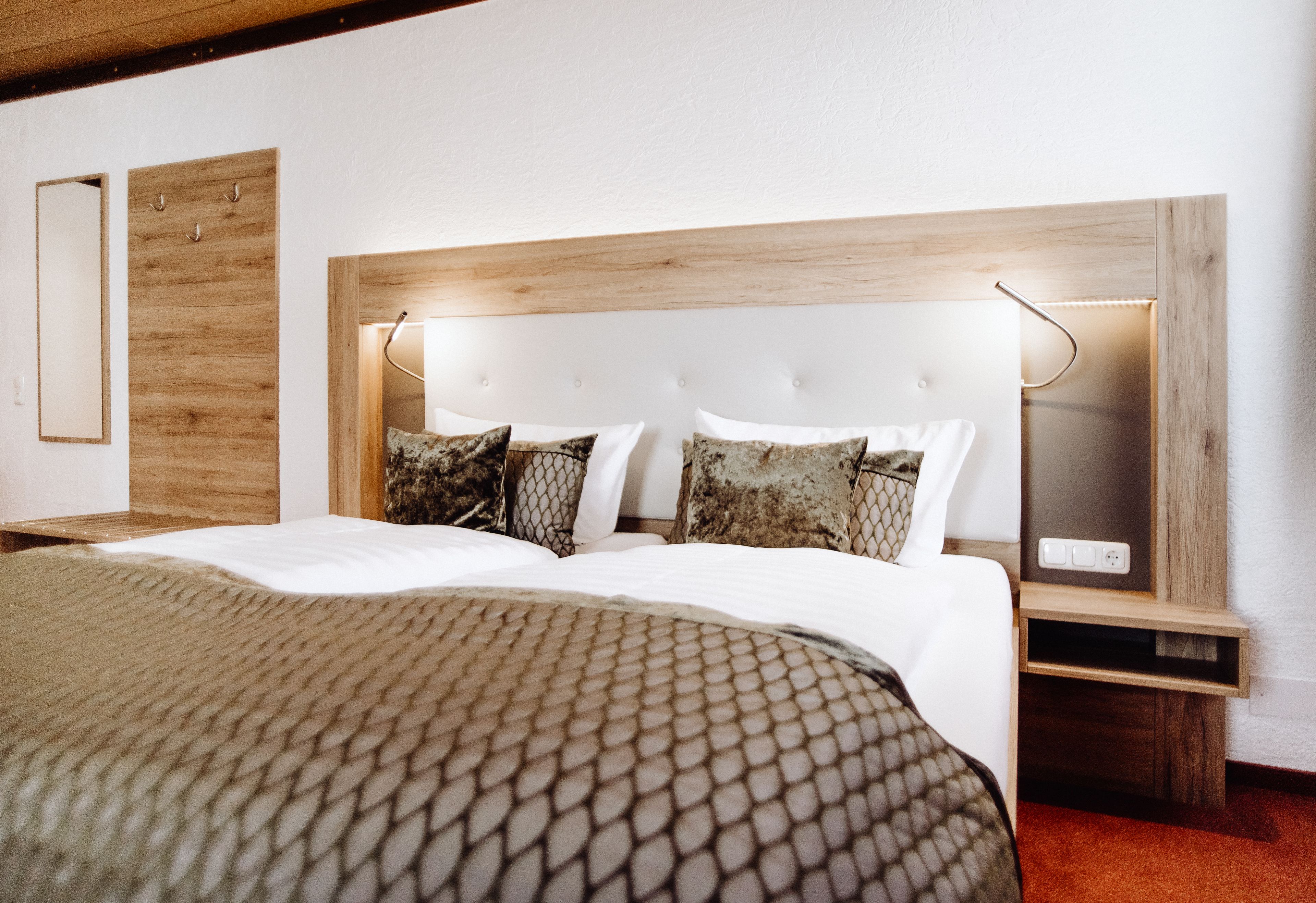 A neatly made bed with a patterned bedspread, a wooden headboard, and bedside lamps.