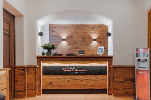 A reception desk with a wooden backdrop, a sign indicating 'Hotel Frauenstuben Hof', and a hand sanitizer dispenser. - Hotel Frauensteiner Hof (Frauenstein)