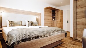 A modern bedroom with a large bed, wooden headboard, built-in wardrobe, and a wooden door. - Hotel Frauensteiner Hof (Frauenstein)