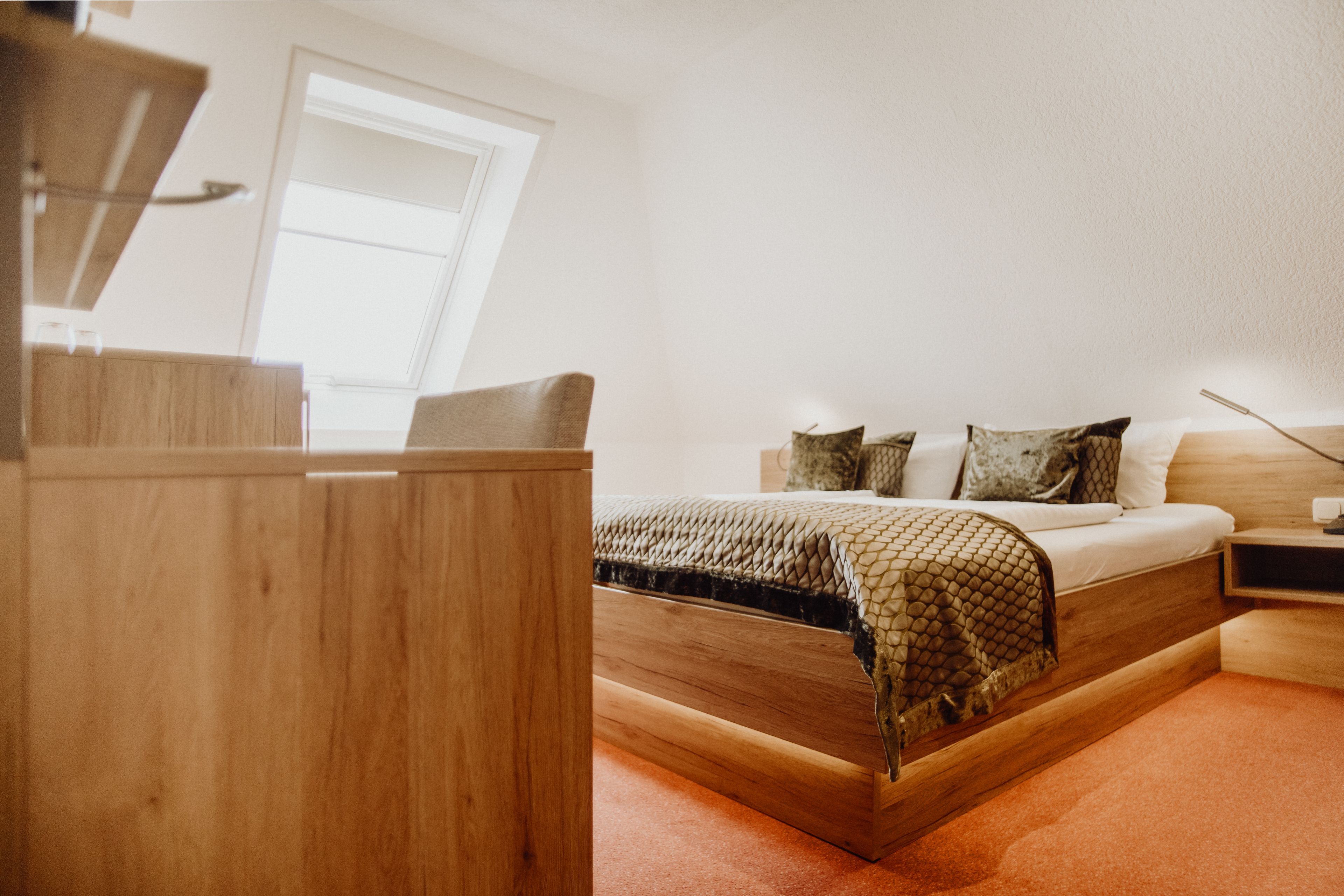 Een slaapkamer met een houten bed, een nachtkastje en een bureau.