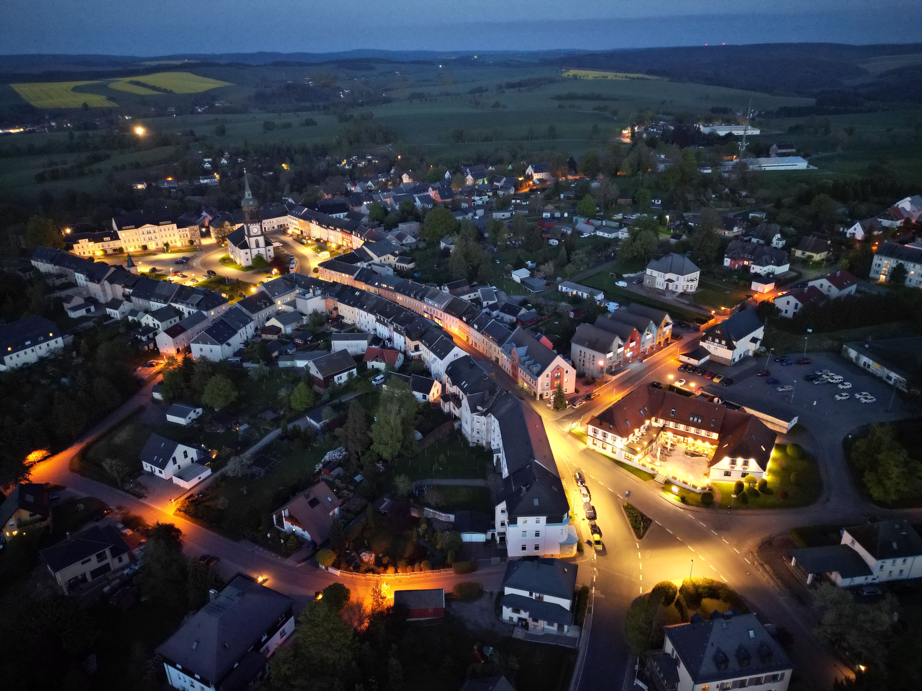 Ein Luftbild einer Stadt mit einer markanten Kirche, einer Hauptstraße und Wohngebäuden.