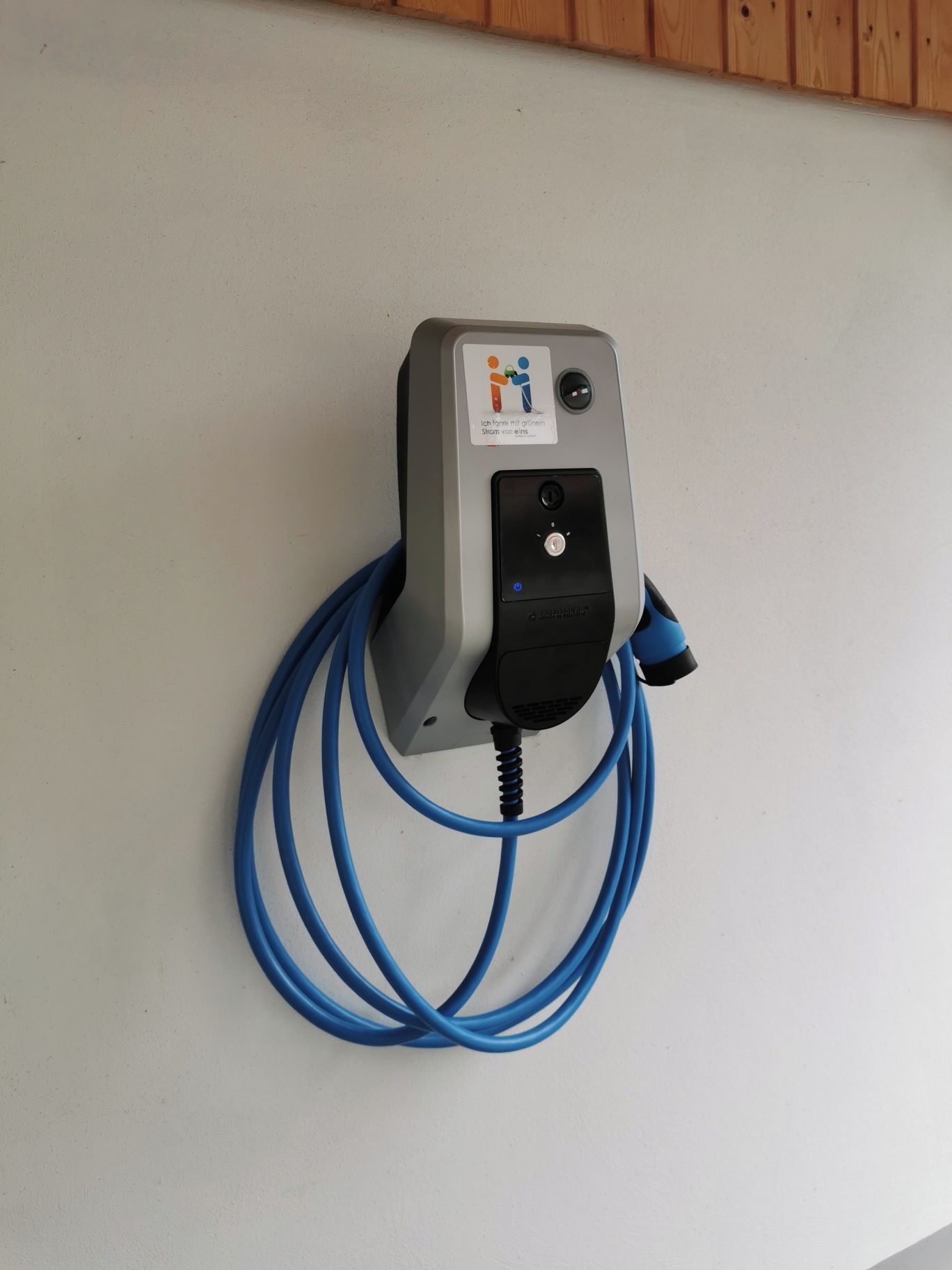 Dispositivo fijado a la pared con un enchufe y un cable enrollado.