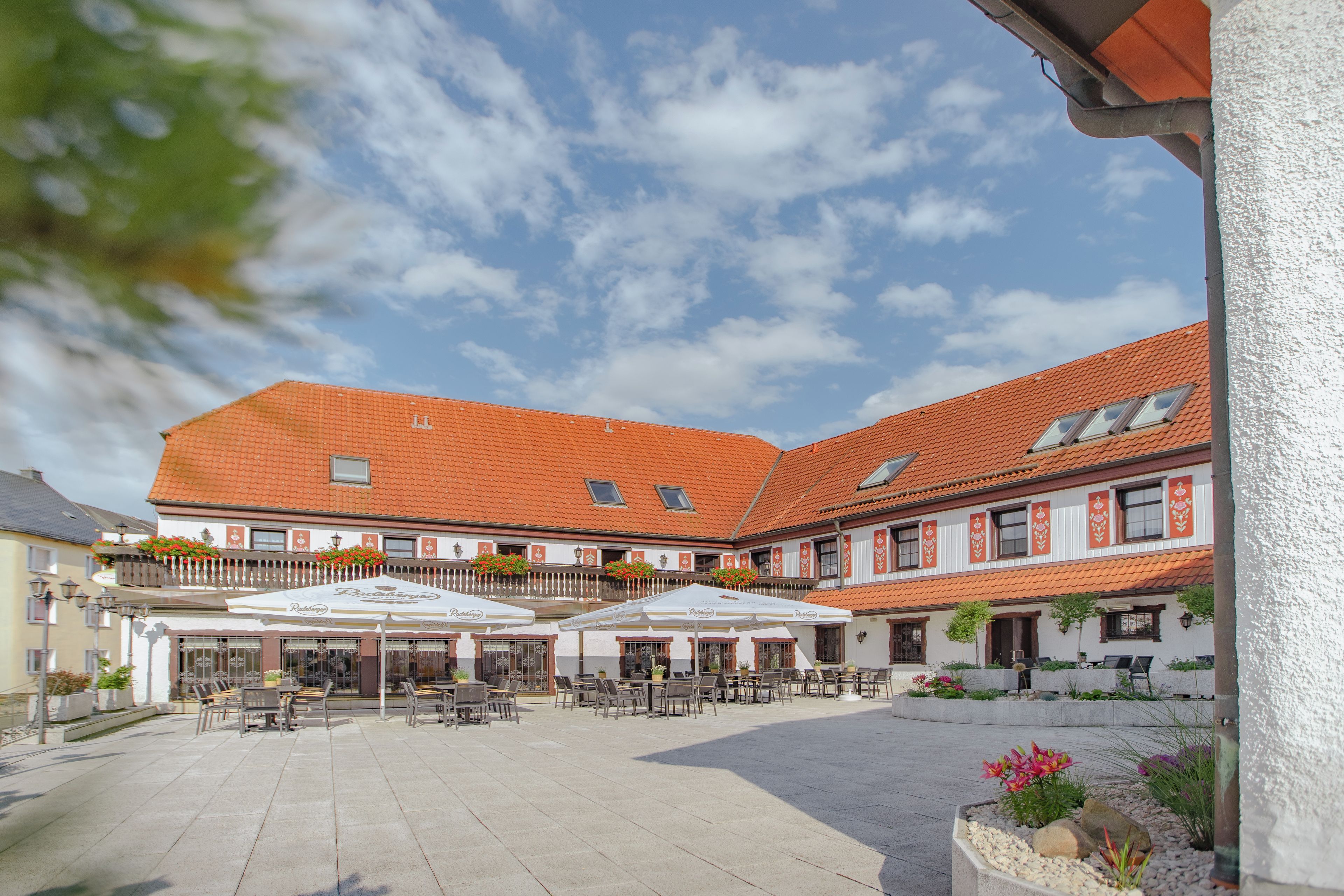 A courtyard with outdoor seating and a building with a red-tiled roof.