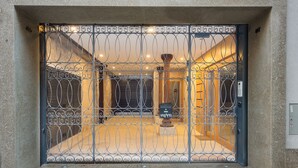 A metal gate with a decorative pattern, a mailbox, and a light fixture above the door. - Almada Domus (Porto)
