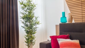 A modern living room with a dark sofa, a potted plant, and a wooden slatted ceiling. - Almada Domus (Porto)