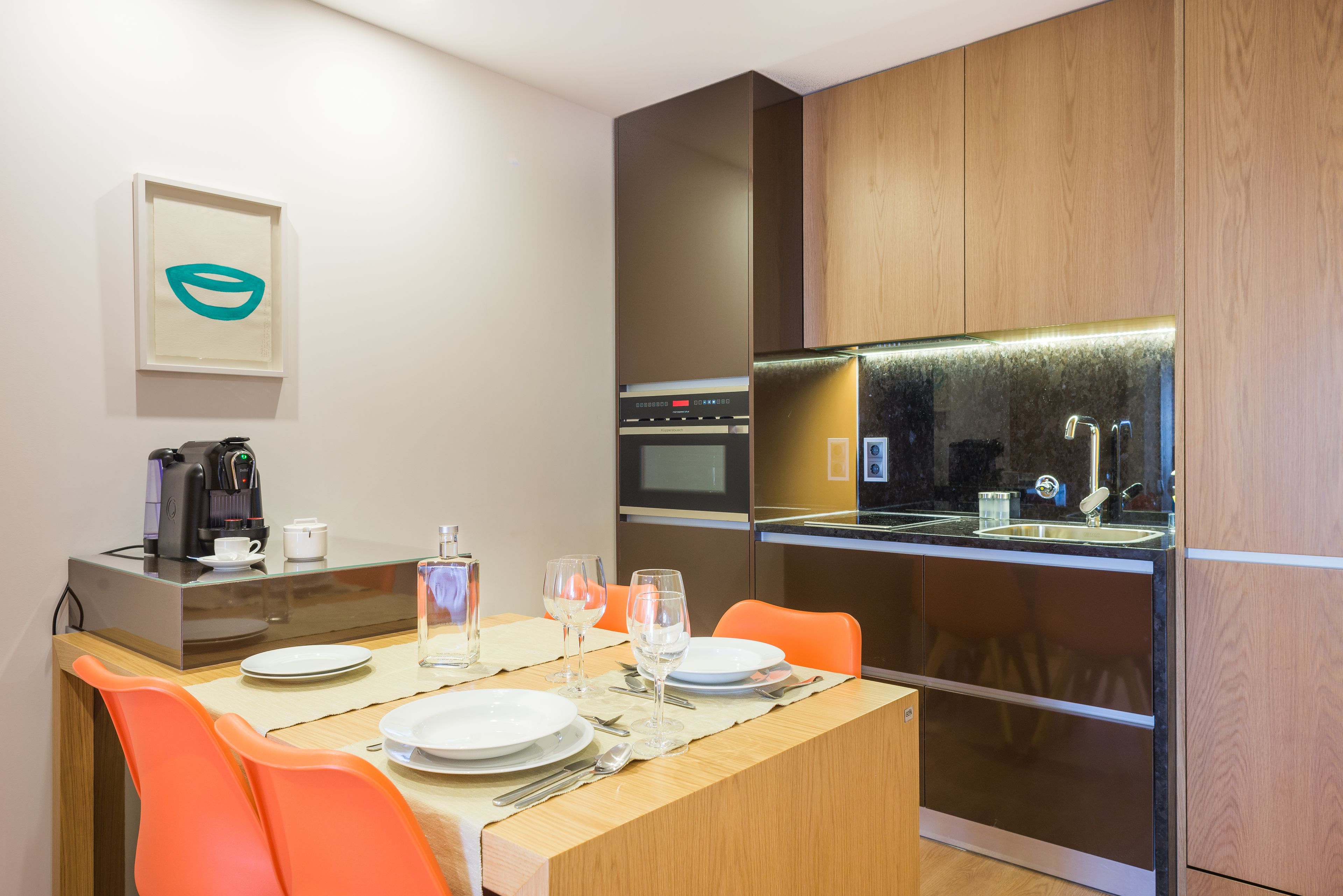 A modern kitchen with a dining area, equipped with a coffee maker, microwave, and oven.