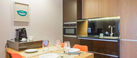 A modern kitchen with a dining area, equipped with a coffee maker, microwave, and oven.