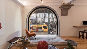 A modern living room with a large arched window, a sofa, a coffee table, and a decorative sculpture.
